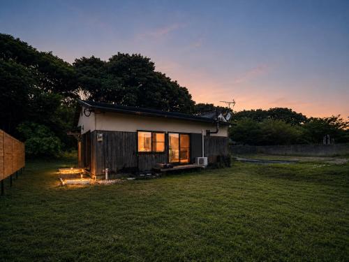 a small house in a field with a sunset at Secret Beach House MOKU in Fukutsu
