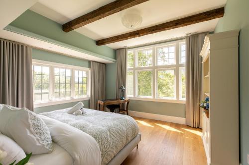 a bedroom with green walls and a bed and windows at Greycliff Mohonk Preserve Getaway in New Paltz