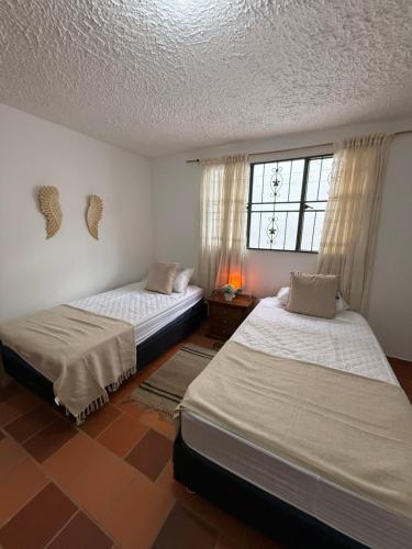 a bedroom with two beds and a window at Habitaciones Stonehaven Ruitoque in Piedecuesta