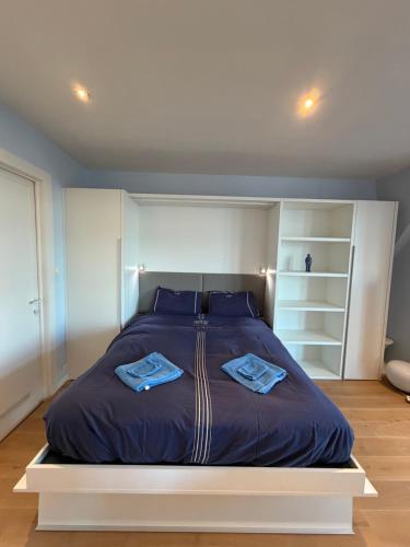 a bedroom with a large bed with two blue pillows at Res. Golf Zoute in Knokke-Heist