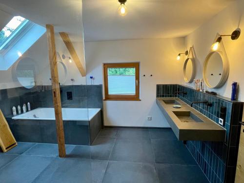 a bathroom with a tub and a sink and mirrors at Kaiserblick Lodge Oberaudorf in Oberaudorf