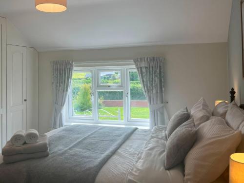 a bedroom with a large bed with a large window at Fron-Haul in Llansantffraid-ym-Mechain