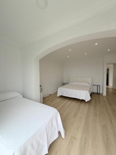 a white bedroom with two beds and wooden floors at Chalet independiente zona Coruxo in Oya