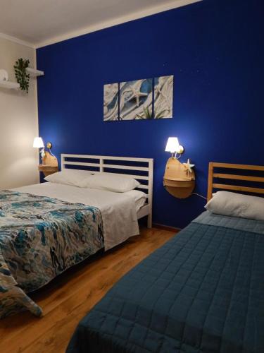 a bedroom with two beds and a blue wall at Suli e Sali Apartment in Calatabiano