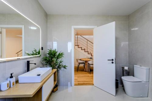 a bathroom with a sink and a toilet and a staircase at The Frenchie's House in Rabo de Peixe