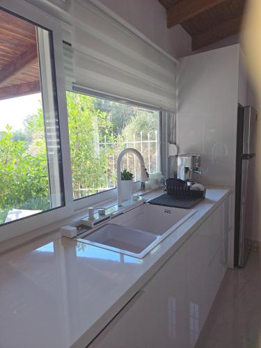 a white kitchen with a sink and a window at Ktima Voulme in Kavála