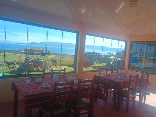 a dining room with a table and chairs and large windows at Luquina homestay in Puno