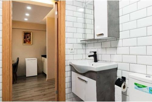 a bathroom with a sink and a white tiled wall at Saltanat Apartment in Istanbul