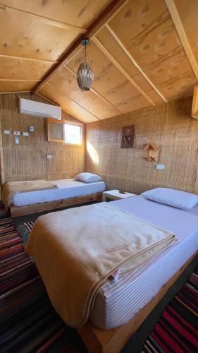 two beds in a room with wooden ceilings at Genena Eco-lodge in Nuweiba