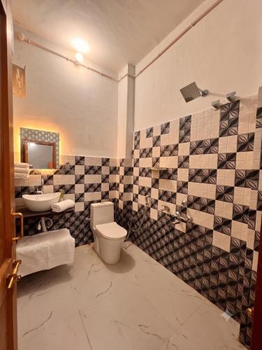 a bathroom with a black and white tiled wall at Ramaya Retreat Ayodhya in Faizābād
