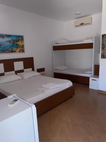 a small bedroom with two beds and a refrigerator at Vila Hana in Dhërmi