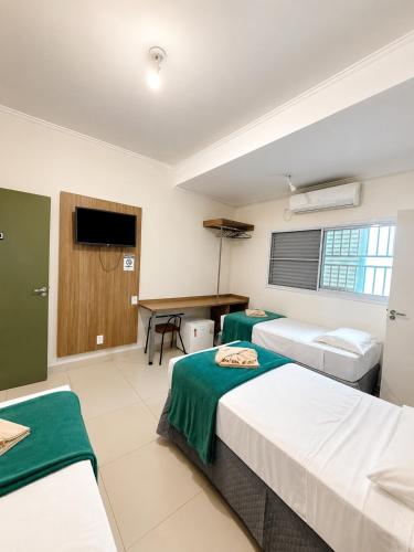 a hotel room with two beds and a desk at Emburi Hotel in Piratininga