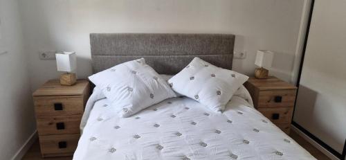 a bedroom with a bed with white sheets and pillows at Espectaculares Aptos Castillo de Bellver in Camas