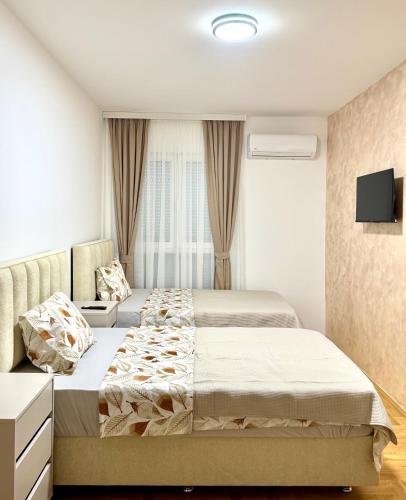 a bedroom with two beds and a tv on the wall at apartment Danijela in Radanovići