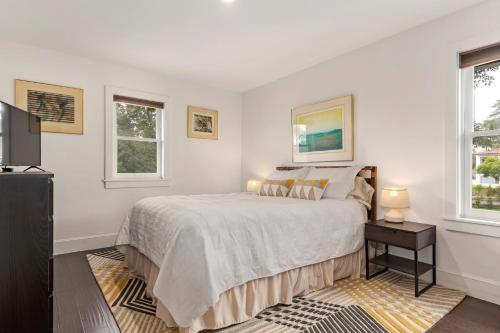 a white bedroom with a bed and two windows at California Comfort in Santa Barbara