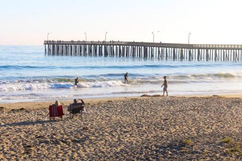 a group of people on a beach with a pier at Blue Door Retreat in Cayucos
