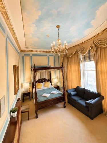 a bedroom with a bed and a couch and a chandelier at 12A Regency Square in Brighton & Hove