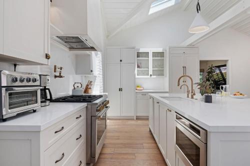 a kitchen with white cabinets and a stove top oven at Hedgerow Jewel Box in Santa Barbara