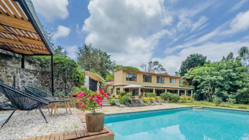 a home with a swimming pool and a house at Refugio del Colibrí in Tepoztlán