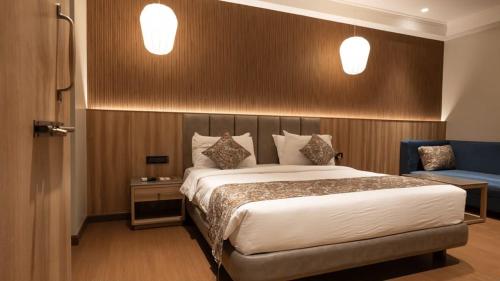 a bedroom with a large bed and a blue chair at Luxury Hotel Aura Residency in Rāiwāla