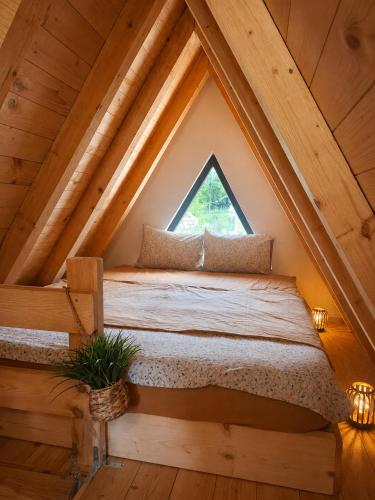 a bed in the attic with a window at Vikendica AS22 in Žabljak