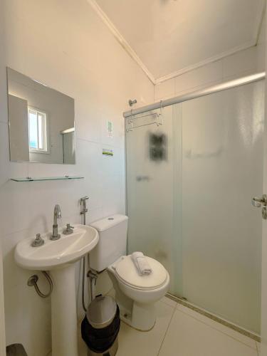 a bathroom with a toilet and a sink and a shower at Emburi Hotel in Piratininga