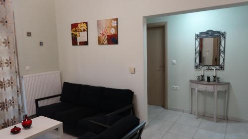 a living room with a black couch and a mirror at Isidoros House in Keramoti