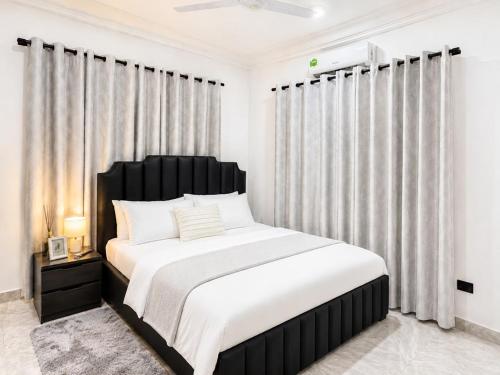 a bedroom with a black and white bed and curtains at Naso Luxe Homes in Sakumona