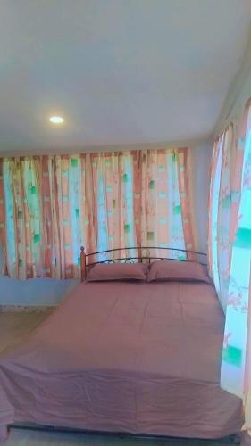 a bedroom with a bed with pink sheets and windows at Nasau Holiday Apartment in Sigatoka