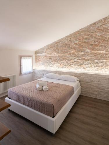 a large bed in a room with a brick wall at Chioggia Apartment in Chioggia