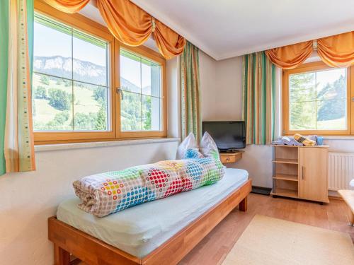 a bedroom with a bed with a television and windows at Hintermühltalhof in Itter