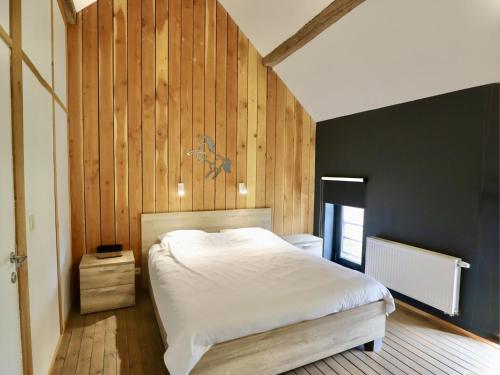 a bedroom with a white bed and wooden walls at Relais de Zoé in Gesves