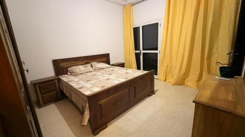 a bedroom with a bed and a window with yellow curtains at Adelhouse in Saint-Louis