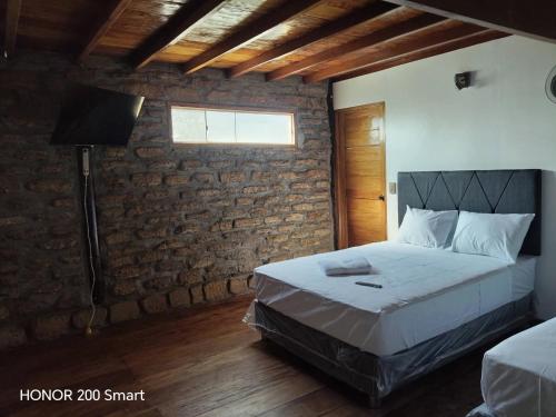 ein Schlafzimmer mit einem Bett und einer Ziegelwand in der Unterkunft Maderobeach1 in Máncora