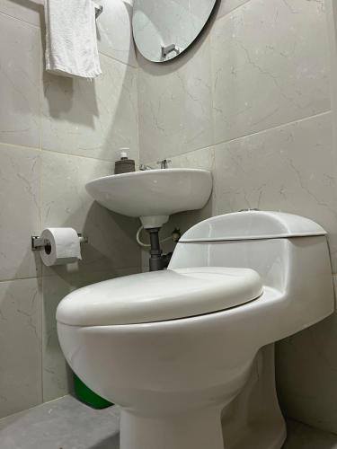 a bathroom with a white toilet and a sink at Hostal La Bendición Buritaca in Santa Marta