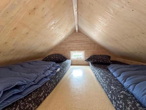 two beds in a room with wooden walls at Surfers Cabin in Ellemeet
