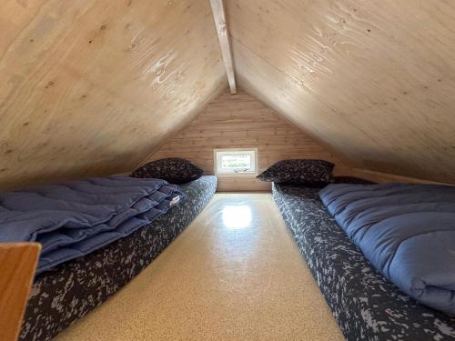 two beds in a room with wooden walls at Sandy Seven in Ellemeet