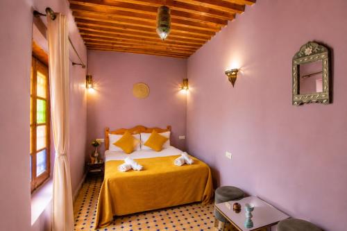 a bedroom with a bed with yellow sheets and purple walls at Riad Mozaik Fes in Fez