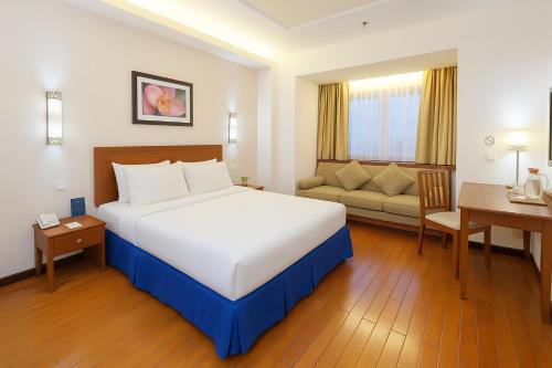 a hotel room with a large bed and a desk at Grand Orchid Hotel Solo in Solo