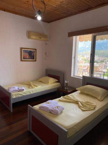 two beds in a room with a window at Flowers House in Gjirokastër