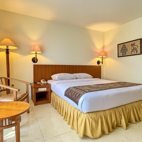 a bedroom with a large bed with a table and a table sidx sidx at Baron Indah Hotel Solo in Grogol