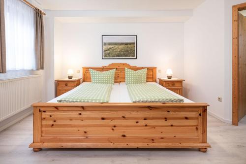 a bedroom with a large wooden bed with green pillows at Winzerhof Nagel in Dettelbach