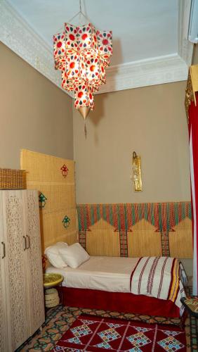 a bedroom with a bed and a chandelier at Maison Céline in Sousse