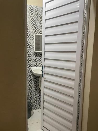 a bathroom with a white door and a sink at Hospedagem M in Barreirinhas