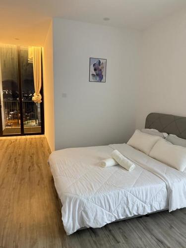 a white bed in a white bedroom with a window at Podium aparment in Kuching