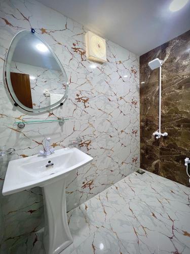 a bathroom with a white sink and a mirror at Hotel Regent DHA in Karachi