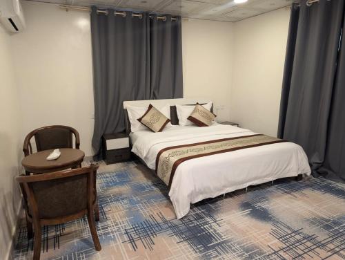 a bedroom with a bed with a table and a chair at شقق دانة ليالينا المخدومه in Al Namas