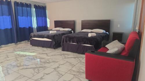 a hotel room with two beds and a red chair at mi casa tropical in Hacienda Santa Clara