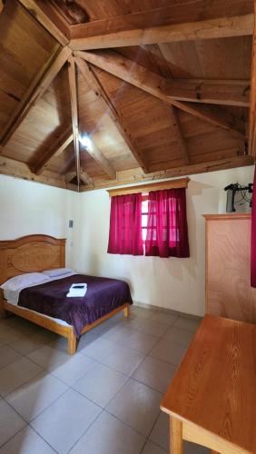 a bedroom with a bed and red curtains at Cabaña Oasis Ixmiquilpan in Ixmiquilpan