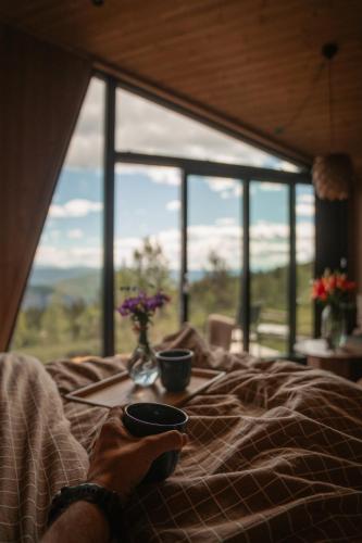a person laying in bed with two cups on a tray at Hylja Lodge in Vaga